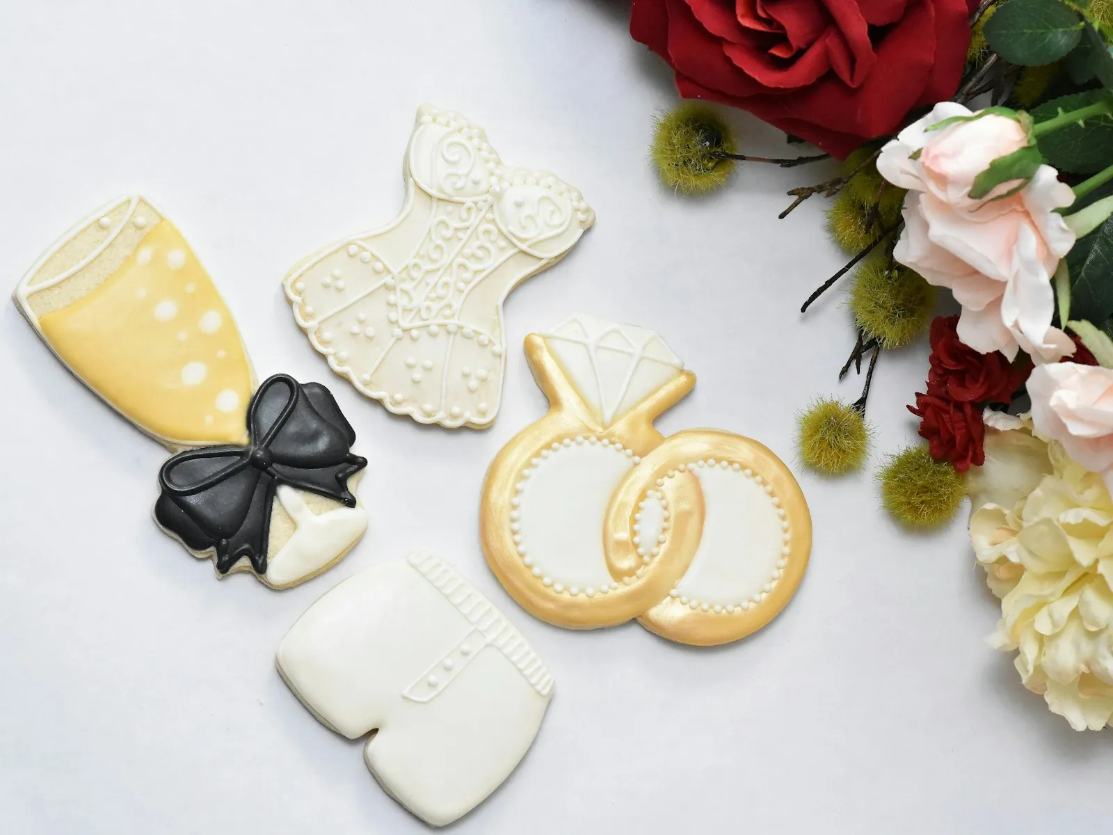 Ivory sugar cookies finished with piped royal icing lace, ribbon and pearl detailing