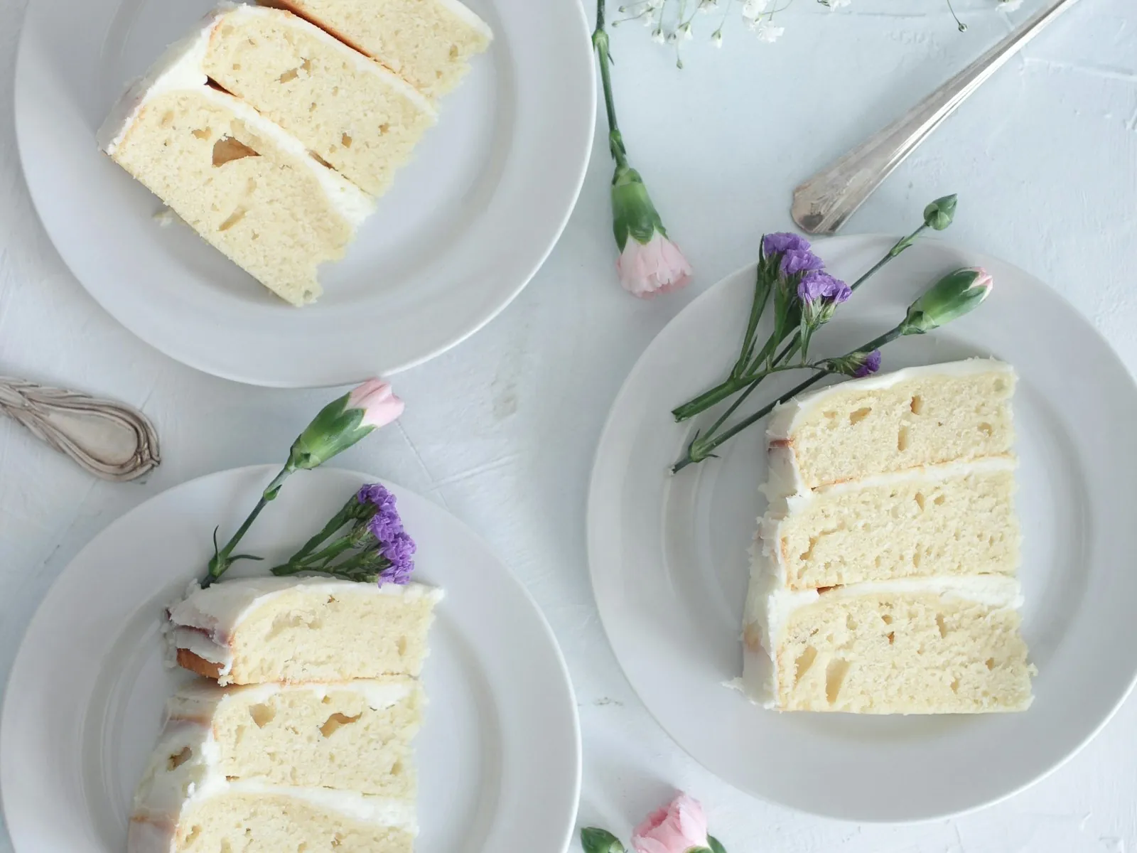 Pale lemon chiffon cake slices plated with sprigs of fresh lavender
